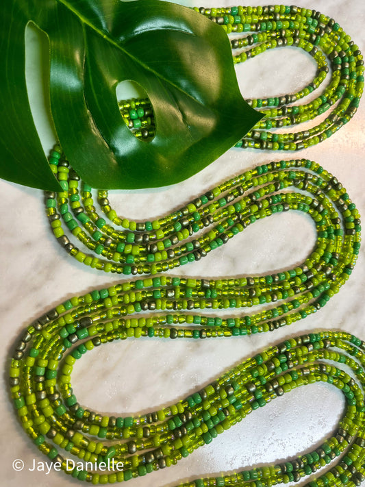 Photo of green pastures traditional African tie on waist beads in gold standard size which fits most up to plus size. Beads are multiple shades and finishes of green. 